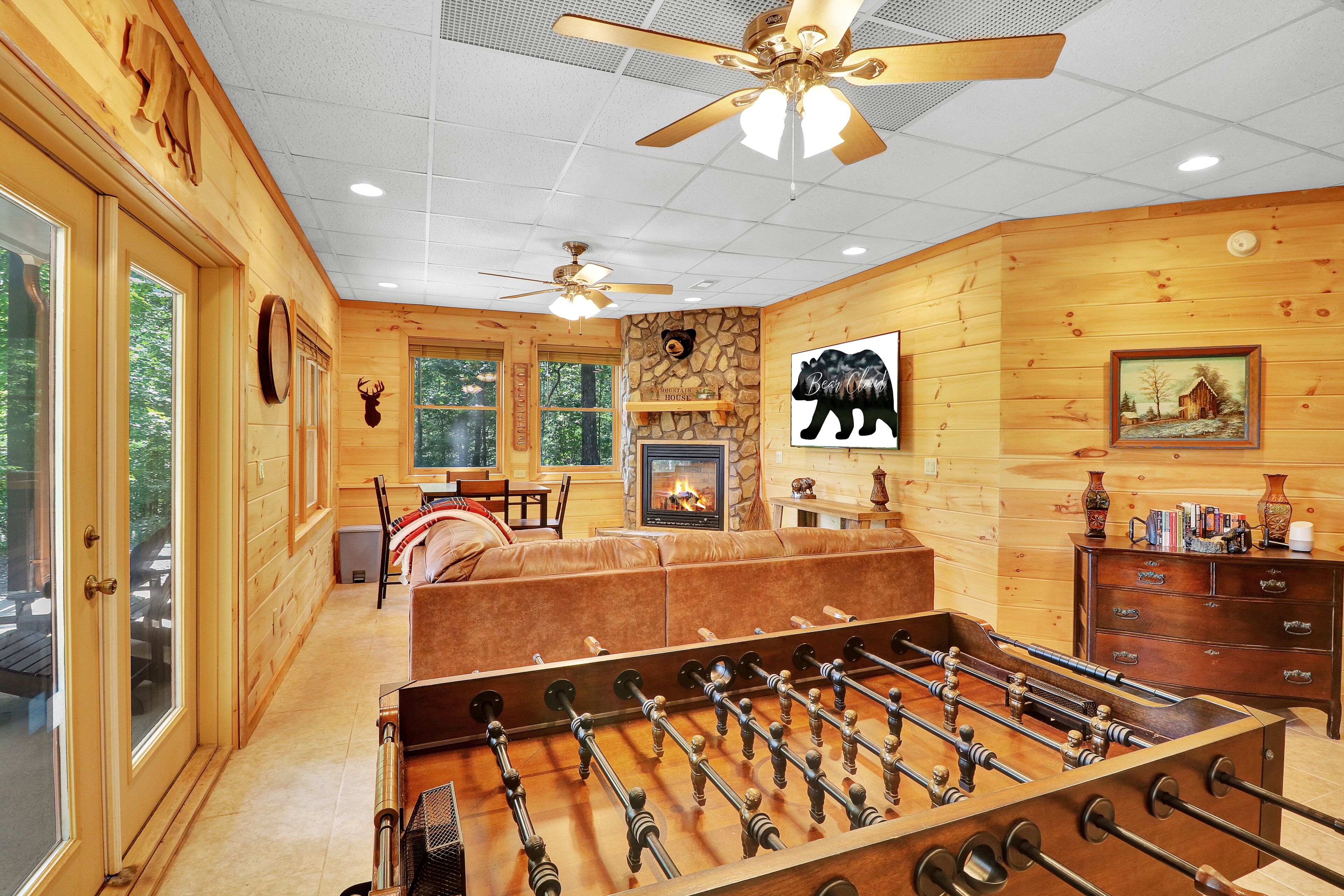 A cozy wooden cabin with a foosball table, a fireplace, and a bear-themed decor.