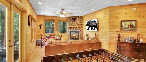 A cozy wooden cabin with a foosball table, a fireplace, and a bear-themed decor.