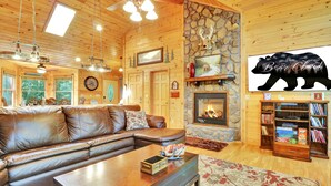 L’intérieur d’un chalet confortable, avec un canapé en cuir, une cheminée et une bibliothèque.