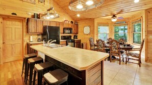 L’intérieur d’un chalet en bois comprend une cuisine, un coin repas et des tabourets de bar.