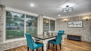 Comedor con pared de piedra, ventanas amplias y mesa con sillas.