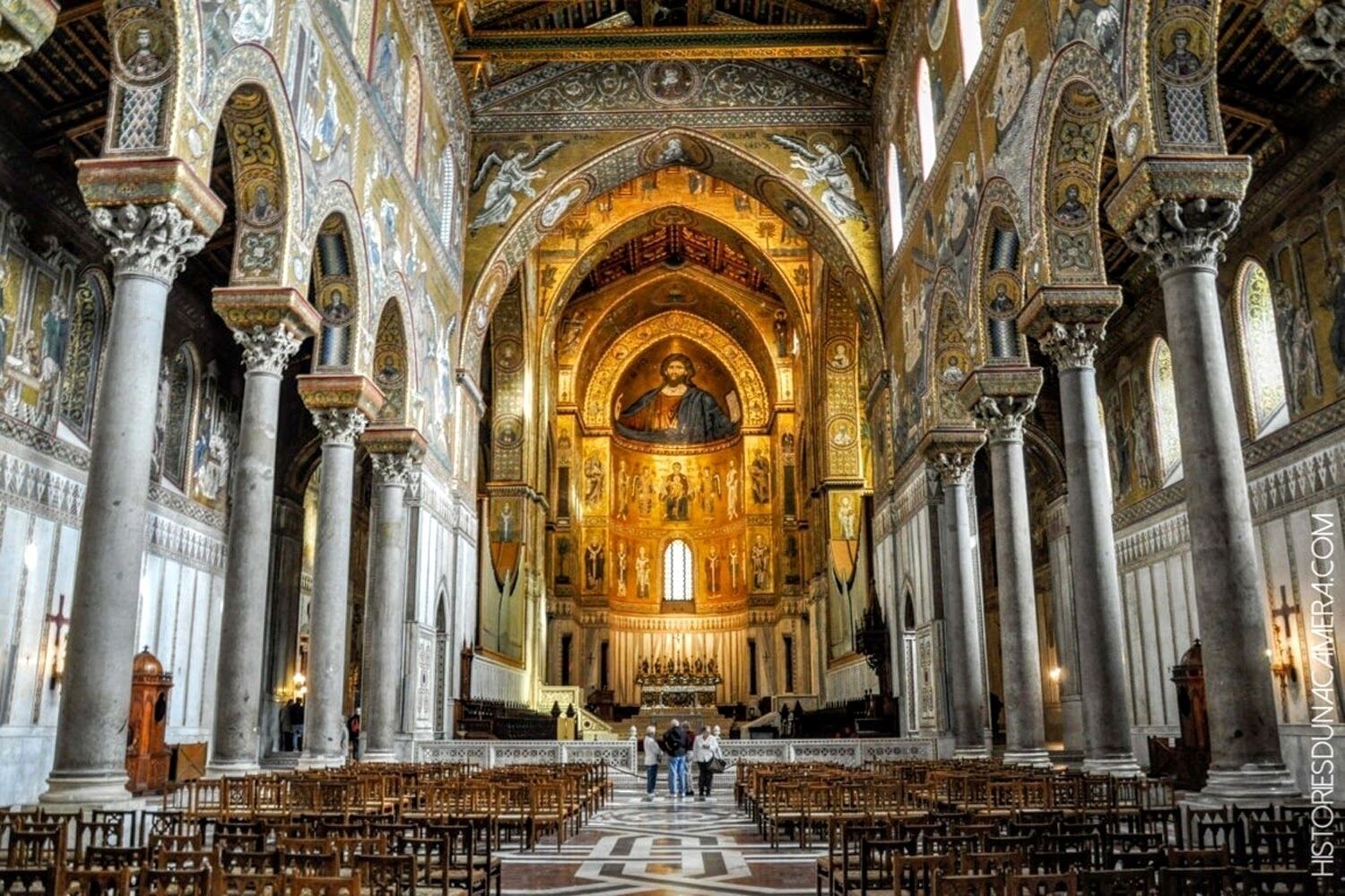 An interior of a grand cathedral with high vaulted ceilings, ornate columns, and a central altar.