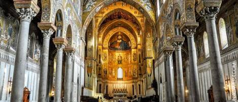 An interior of a grand cathedral with high vaulted ceilings, ornate columns, and a central altar.