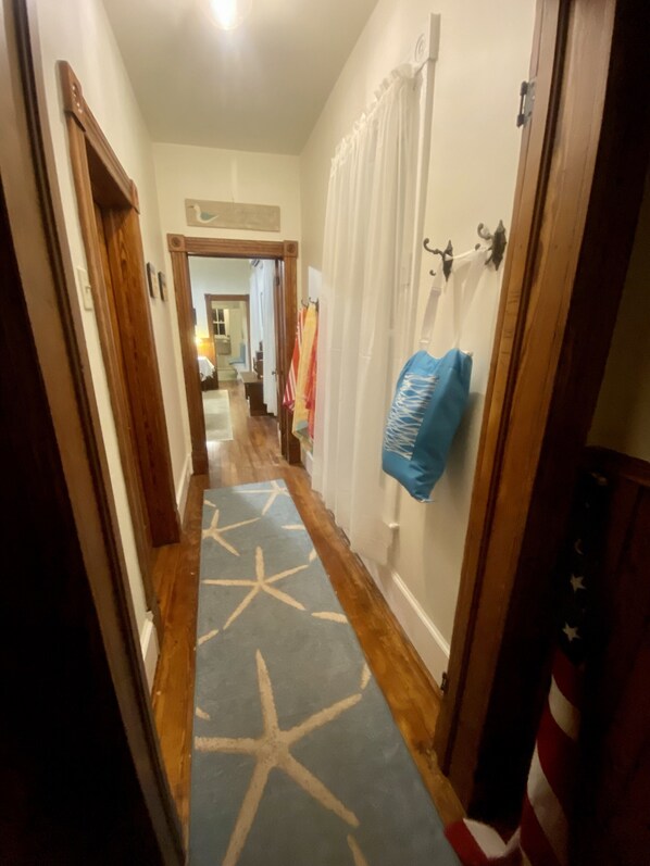 A hallway with a star-patterned carpet, wooden doors, and a view into another room.