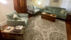 Una sala de estar con un alfombra estampado, dos sofás, una mesa de centro y una puerta de madera.