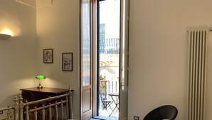 A hotel room with a bed, a desk with a lamp, a chair, and a view of the outside balcony. - DIMORA SANTA CROCE Newly renovated apartment in the historic center of Lecce (Lecce)