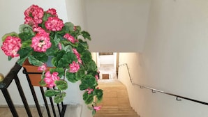 A staircase with a black handrail, a potted plant with pink flowers, and a white wall. - DIMORA SANTA CROCE Newly renovated apartment in the historic center of Lecce (Lecce)
