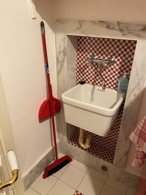 A bathroom with a white sink, red checkered tiles, a red broom, and a bottle of hand soap. - DIMORA SANTA CROCE: Recently renovated apartment in the historic center of Lecce (Lecce)