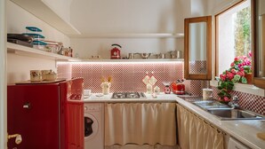 A compact kitchen with a red refrigerator, a washing machine, a stove, and a sink. - DIMORA SANTA CROCE Newly renovated apartment in the historic center of Lecce (Lecce)