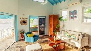 Une pièce avec un plafond bleu, un canapé blanc, un fauteuil bleu, un meuble en bois et une petite table.