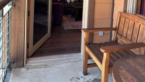 Um banco de madeira e uma porta de vidro que dá para uma sala de estar com sofá e mesa de centro.