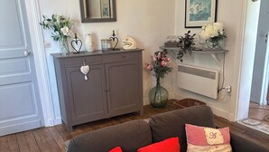 A living room with a grey sofa, red cushions, a mirror, a framed picture, and a vase with flowers. - Villa des Genêts (Montagrier)