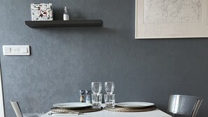 Una mesa de comedor con sillas de vidrio transparente, un mantel blanco y una botella de agua sobre una repisa.