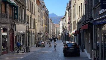 A cobblestone street lined with historic buildings, some with shops and cafes.
