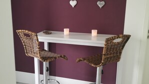 A dining area with two wicker chairs and a white table, featuring a decorative wall piece above. - Panoramablick Nahe Oberhof (Geratal)