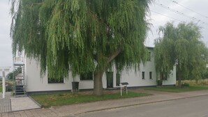 A modern building with a large weeping willow tree in front. - Panoramablick Nahe Oberhof (Geratal)