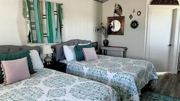 A bedroom with two beds, a bedside table, a lamp, a mirror, and wall decorations.
