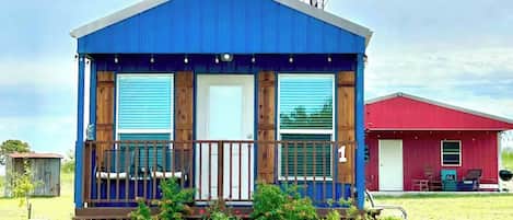 Eine kleine, eingeschossige Holzhütte mit blauer Fassade und einer Holzterrasse.