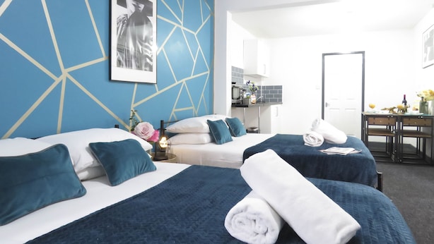 A hotel room with two beds, a desk, and a kitchenette. - Tudors Inn Handsworth (Birmingham)