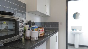 A kitchen with a built-in oven, a sink, and cabinets. - Tudors Inn Handsworth (Birmingham)