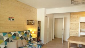 Una habitación acogedora con un sofá de estampado geométrico, una pared de madera, una mesita y una estantería.