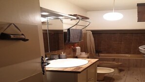 Un baño con tocador de madera, lavamanos, inodoro y bañera.