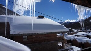Un pueblo en la montaña cubierto de nieve, con edificios de madera y cascadas de hielo colgando de los aleros.