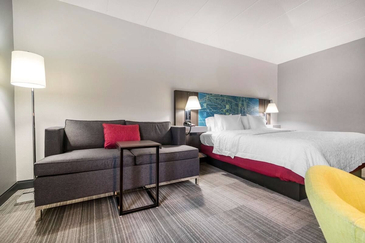 A hotel room with a bed, a sofa, a chair, and a desk.