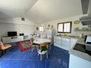 Un espace de vie compact comprenant un coin repas, une kitchenette et un téléviseur à écran plat.