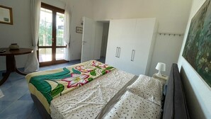 Un dormitorio con cama, armario, escritorio y ventana con cortinas.