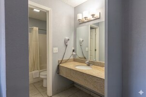 A bathroom with a sink, mirror, and two hair dryers.