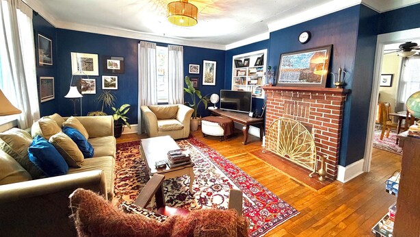 A living room with a sofa, armchairs, a coffee table, a fireplace, and a TV. - Perfect Basecamp! 3b/3bath Historic Downtown 🏡 (Fayetteville)