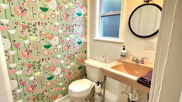 Un baño con inodoro, lavamanos y espejo. Las paredes tienen un estampado floral.