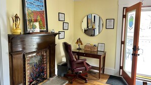 A room with a wooden desk, a chair, a fireplace, and a mirror on the wall. - Perfect Basecamp! 3b/3bath Historic Downtown 🏡 (Fayetteville)