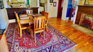 A dining area with a wooden table, chairs, and a patterned rug. - Perfect Basecamp! 3b/3bath Historic Downtown 🏡 (Fayetteville)