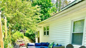 A covered outdoor patio with a sectional sofa, wicker chairs, and a patterned rug. - Perfect Basecamp! 3b/3bath Historic Downtown 🏡 (Fayetteville)
