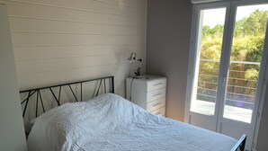 A bedroom with a bed, a dresser, a desk with a lamp, and a sliding glass door to the outside. - 3Bed Maisonette/close to beach/Tranquil  (Seignosse)