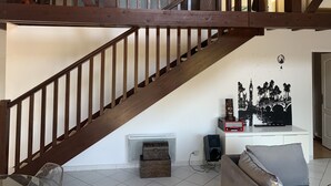 A staircase with wooden beams and a white wall with a black silhouette artwork. - 3Bed Maisonette/close to beach/Tranquil  (Seignosse)