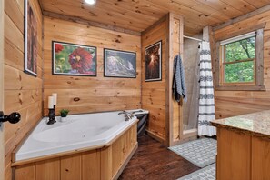 A wooden cabin bathroom with a bathtub, a sink, a shower, and framed pictures on the wall.