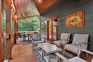A wooden deck with outdoor seating, a table, and a wall-mounted artwork.