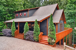 A cabin with a steep roof, a front porch, and a wooden deck.