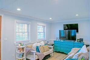 Relax in this spacious living room with a large flat-screen TV, comfortable sofa, and stylish dresser.
