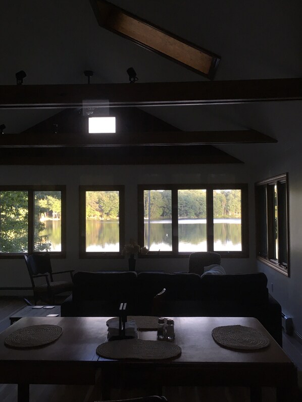 A dining area with a table, chairs, and a view of a lake through large windows.