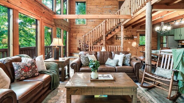 A spacious log cabin interior with a large living area, a staircase, and a dining area. - 15 Min. to Dollywood · Sauna · Hot Tub · Pool Table · Arcade • Foosball • Grill (sevierville)