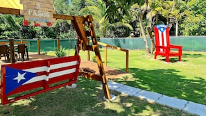 Relax in a serene outdoor space surrounded by lush tropical vegetation and a wooden swing set.