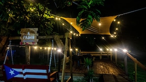 Relax in the serene outdoor space surrounded by lush greenery and twinkling string lights.