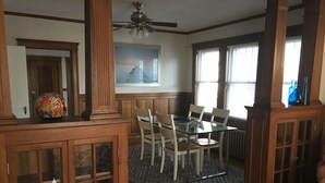 A dining area with a glass table, wooden chairs, and a patterned rug. - Casa de Los Clarey • Boston • Logan • Beaches • Free Parking (Winthrop)
