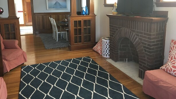 A living room with a fireplace, a television, and a dining area with chairs and a table. - Casa de Los Clarey • Boston • Logan • Beaches • Free Parking (Winthrop)