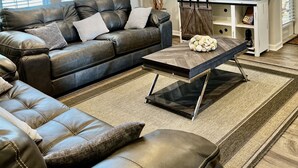 Una sala de estar moderna con un sofá de cuero, una mesa de centro y un televisor sobre un mueble.