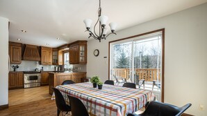 Een ruime keuken met houten kastjes, een groot eiland en een eethoek met een tafel gedekt voor vier personen.